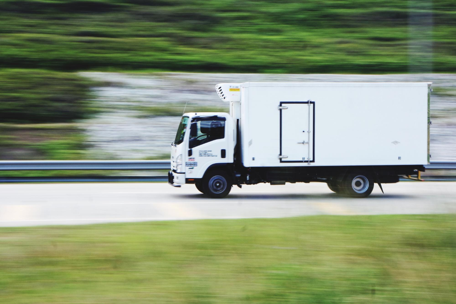 White moving truck driving quickly on a highway, transporting fitness equipment