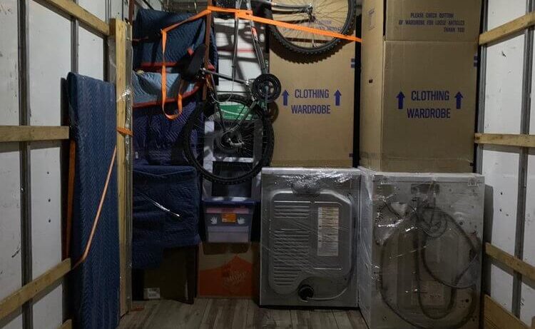 Neatly packed moving truck with home gym equipment, boxes, and bicycles, ready for relocation